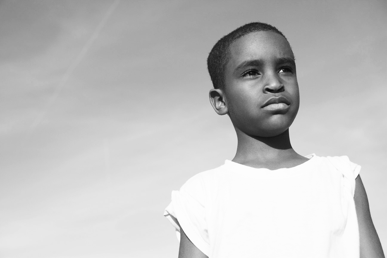Black-and-white portrait of a boy in a white shirt looking toward the sky